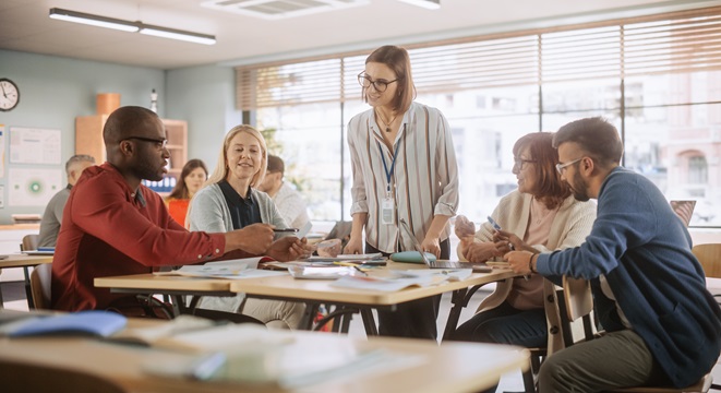 Adult Education Center: Adult Students Learning in Classroom, Working as Two Teams on a Verbal Education Game. Positive Female Teacher Giving Advice, Answering Questions, and Motivating Students